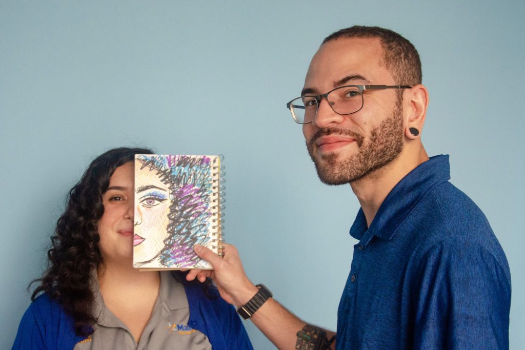 Mailstar designer holding a hand-drawn sketchbook portrait in front of a teammate